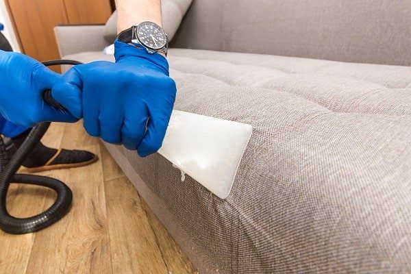 فني ينظف كنب قماشي بجهاز شفط متخصص